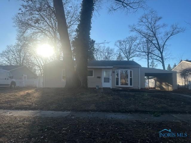 view of front of house featuring an attached carport, fence, and aphalt driveway