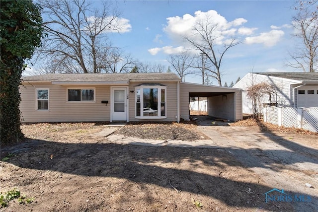 view of front facade with an attached carport and dirt driveway