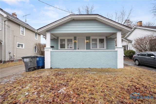 bungalow-style house featuring covered porch and brick siding