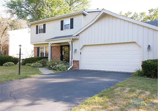 view of front of house featuring aphalt driveway, brick siding, an attached garage, board and batten siding, and a front yard