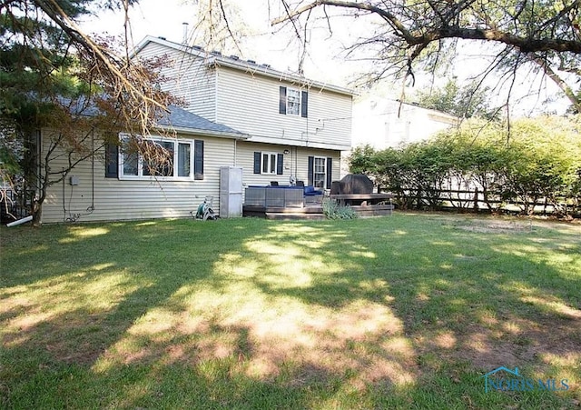 back of property with fence, a deck, and a yard