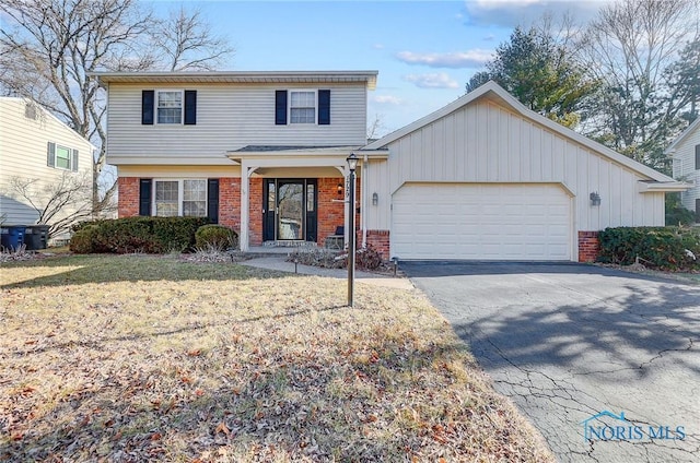 view of front of house with aphalt driveway, a garage, brick siding, and a front yard