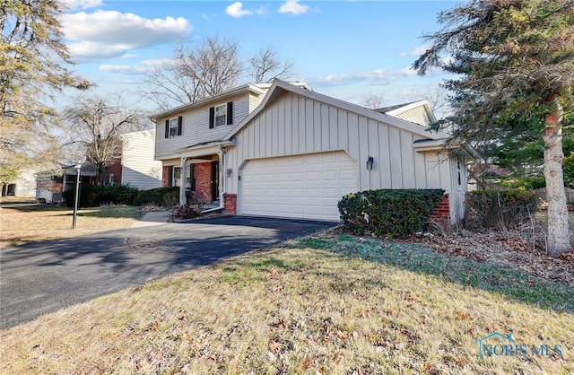 view of front of home featuring board and batten siding, brick siding, an attached garage, and driveway