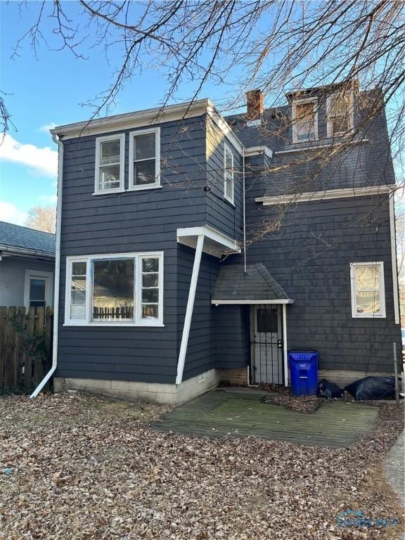 back of property with a chimney and fence
