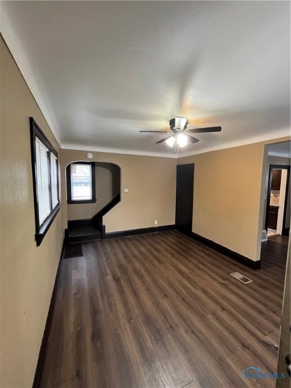 spare room with dark wood-style flooring, baseboards, ceiling fan, and visible vents