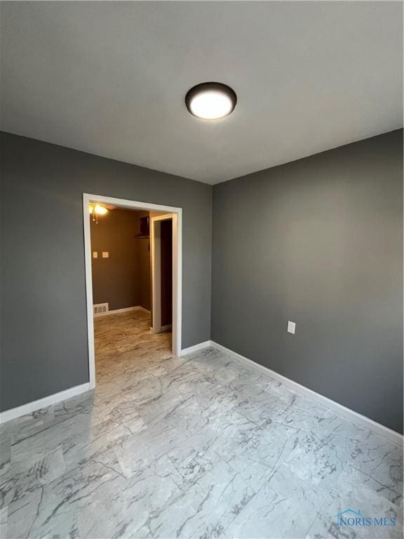 unfurnished room featuring baseboards, marble finish floor, and visible vents