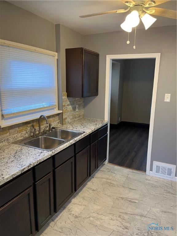 kitchen featuring a sink, a ceiling fan, tasteful backsplash, visible vents, and dark brown cabinets