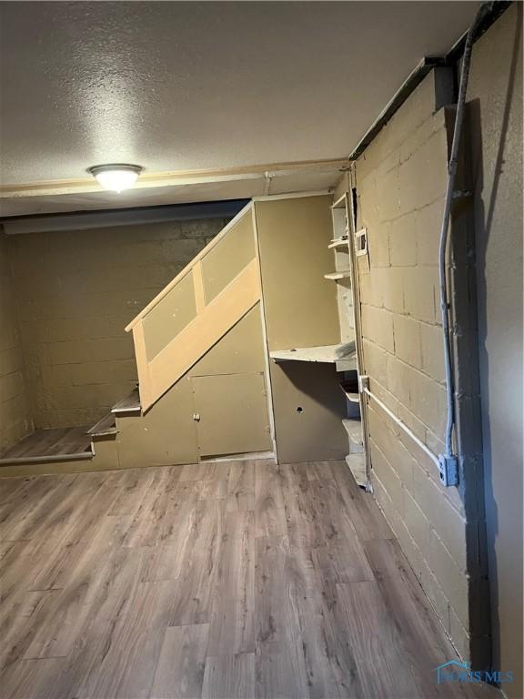 basement with concrete block wall and wood finished floors