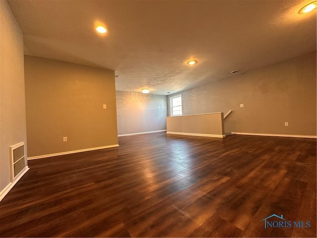 empty room featuring dark wood-style floors, baseboards, and recessed lighting