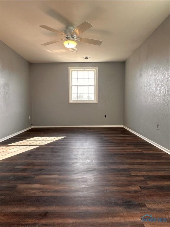 spare room featuring a ceiling fan, baseboards, and wood finished floors