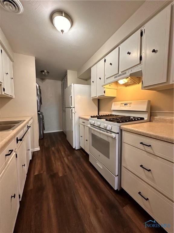 kitchen with white appliances, white cabinets, dark wood-style flooring, under cabinet range hood, and a sink