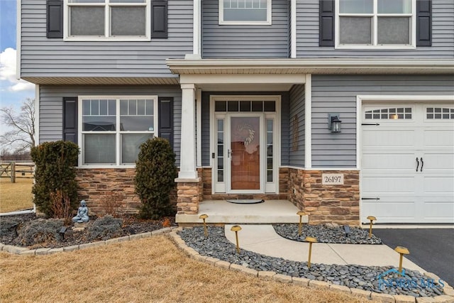 view of exterior entry featuring an attached garage and stone siding