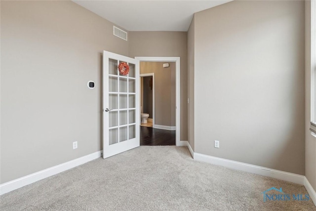 carpeted spare room featuring visible vents and baseboards