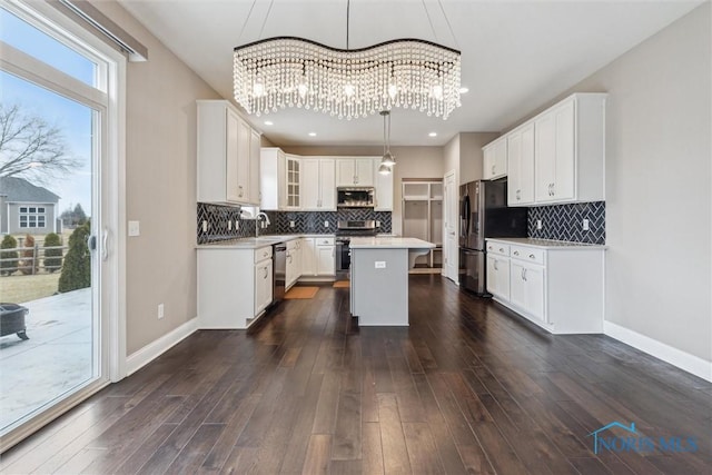 kitchen with dark wood-style flooring, light countertops, an inviting chandelier, appliances with stainless steel finishes, and a kitchen island