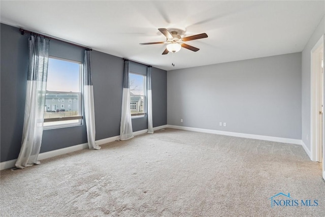 carpeted empty room with ceiling fan and baseboards