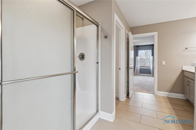 full bathroom featuring tile patterned floors, a shower stall, baseboards, and vanity