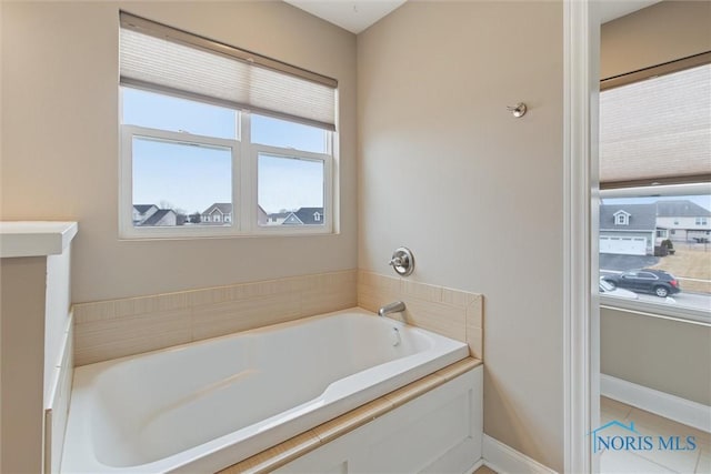 bathroom featuring a garden tub and baseboards