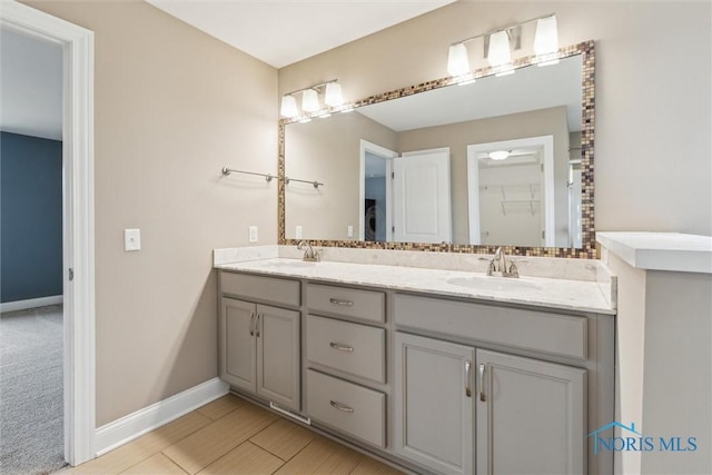 full bathroom featuring double vanity, a sink, and baseboards