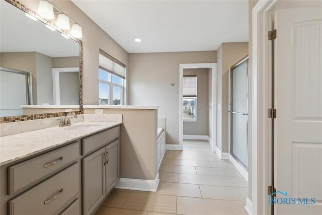 bathroom with a garden tub, recessed lighting, vanity, baseboards, and a shower stall