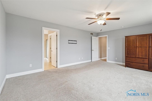 unfurnished bedroom featuring light carpet, visible vents, baseboards, and a ceiling fan