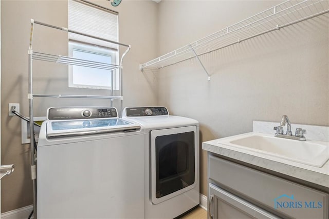 washroom featuring washing machine and dryer, cabinet space, and a sink