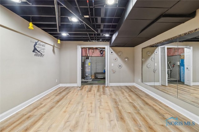 finished basement featuring gas water heater, wood finished floors, and baseboards