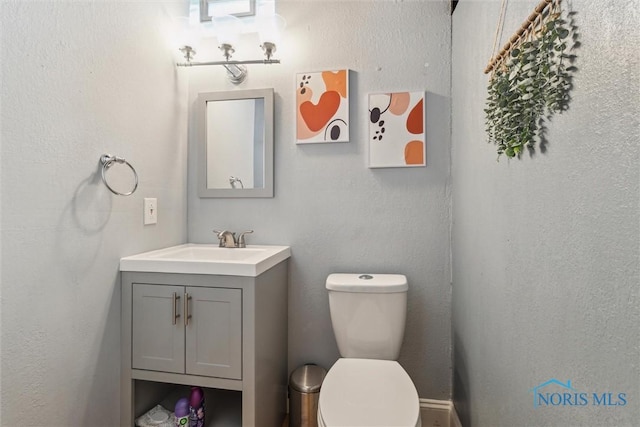 bathroom featuring a textured wall, vanity, and toilet