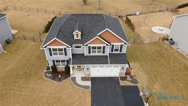 view of front facade with an attached garage, stone siding, driveway, and fence