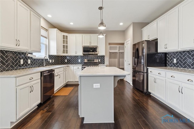 kitchen with dark wood-style floors, stainless steel appliances, light countertops, and a center island