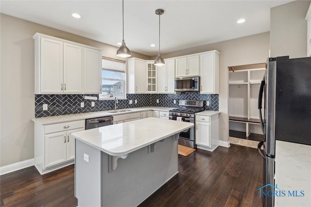 kitchen featuring stainless steel appliances, dark wood-type flooring, a sink, and a center island