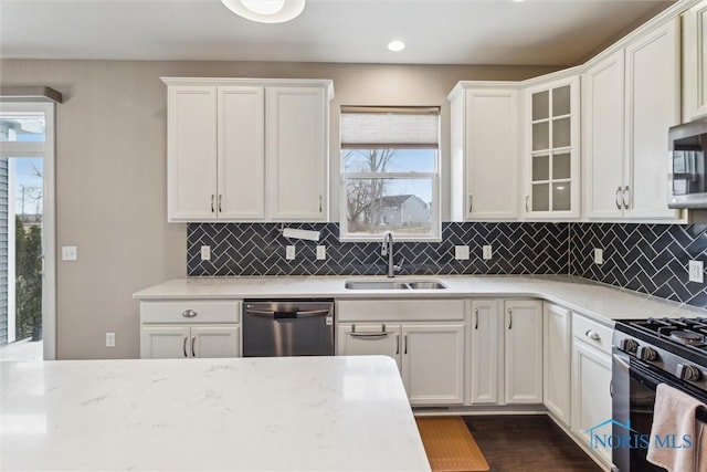 kitchen featuring stainless steel appliances, white cabinets, a sink, and backsplash