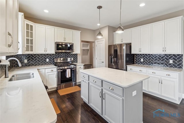 kitchen featuring dark wood-style floors, a kitchen island, stainless steel appliances, white cabinetry, and a sink