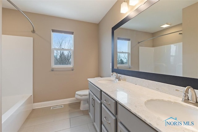 bathroom featuring double vanity, a sink, toilet, and baseboards