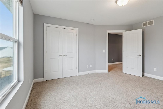 unfurnished bedroom featuring baseboards, carpet, visible vents, and a closet