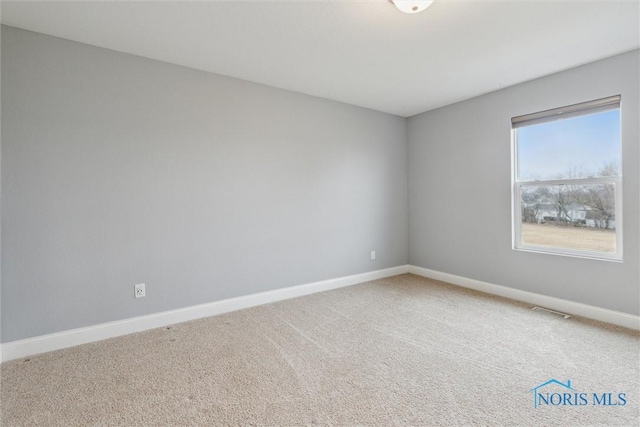 empty room with carpet floors, visible vents, and baseboards