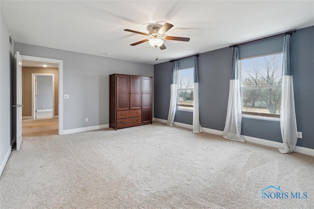 unfurnished bedroom featuring baseboards, a ceiling fan, and light colored carpet