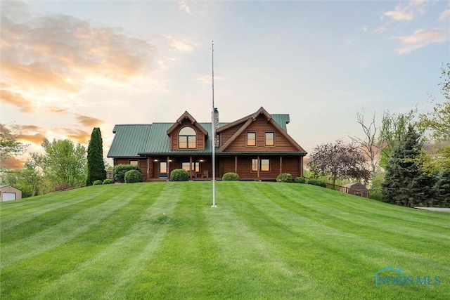 back of property with a chimney, metal roof, and a yard