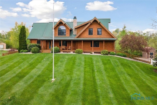 cabin featuring a chimney, fence, metal roof, and a front yard