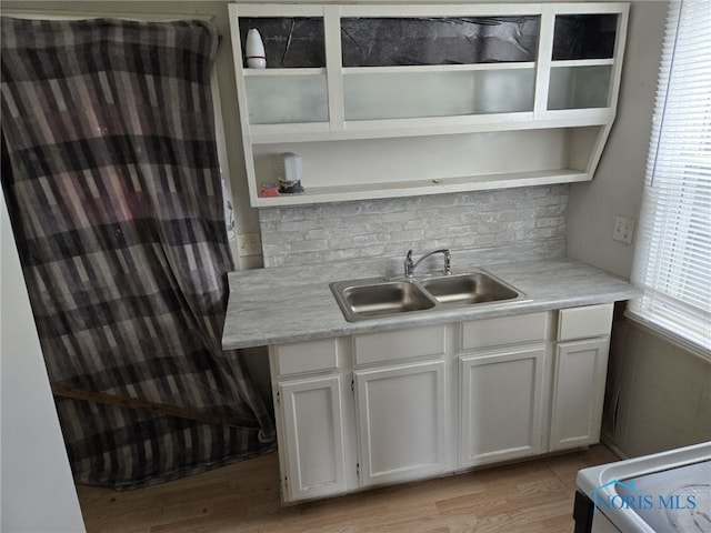 kitchen with a sink, light countertops, tasteful backsplash, and open shelves