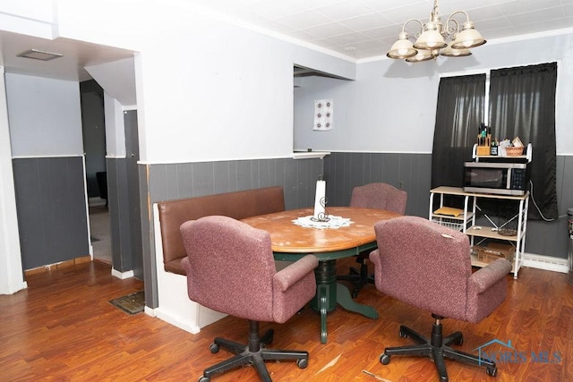 dining area featuring a wainscoted wall, ornamental molding, wood finished floors, and an inviting chandelier