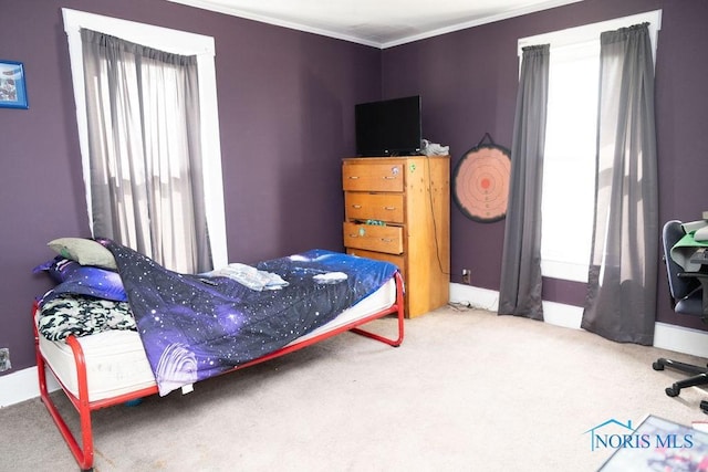 carpeted bedroom with ornamental molding and baseboards