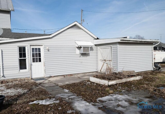 back of house with a shingled roof and an outbuilding