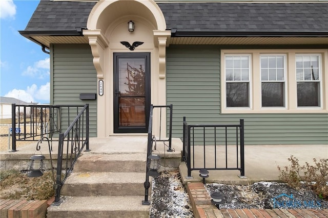 doorway to property with a shingled roof