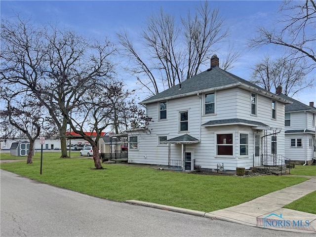 view of front of home featuring a front lawn, a chimney, and a shingled roof