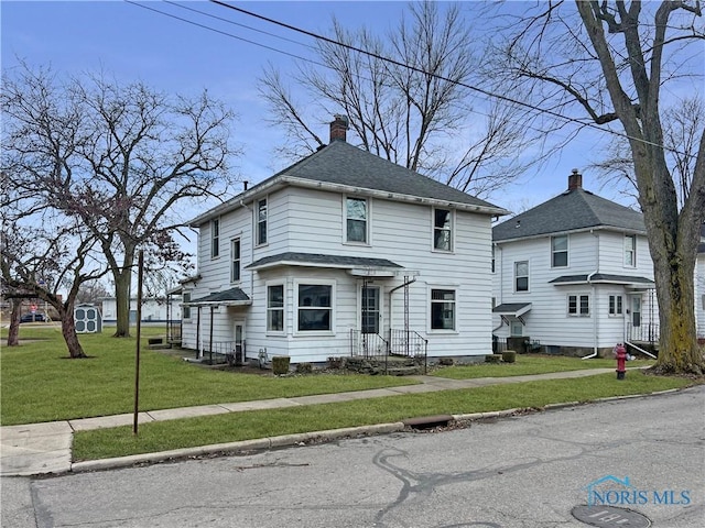 traditional style home featuring a front lawn, a chimney, and a shingled roof