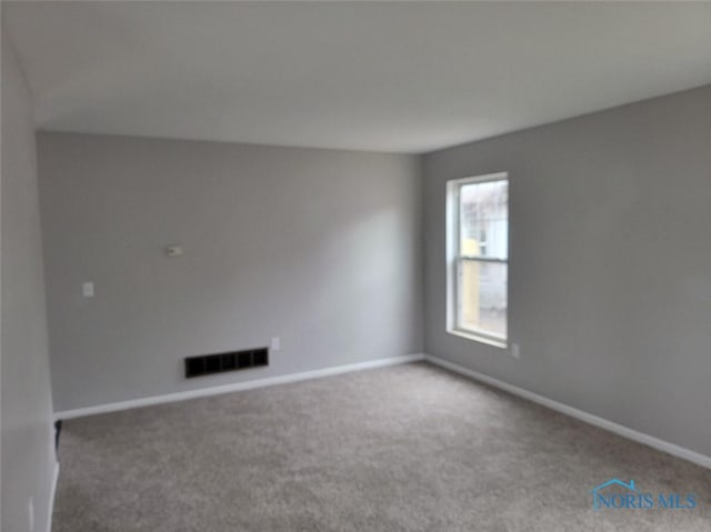 spare room featuring baseboards, visible vents, and carpet flooring