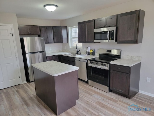 kitchen featuring appliances with stainless steel finishes, light wood-type flooring, light countertops, and a sink