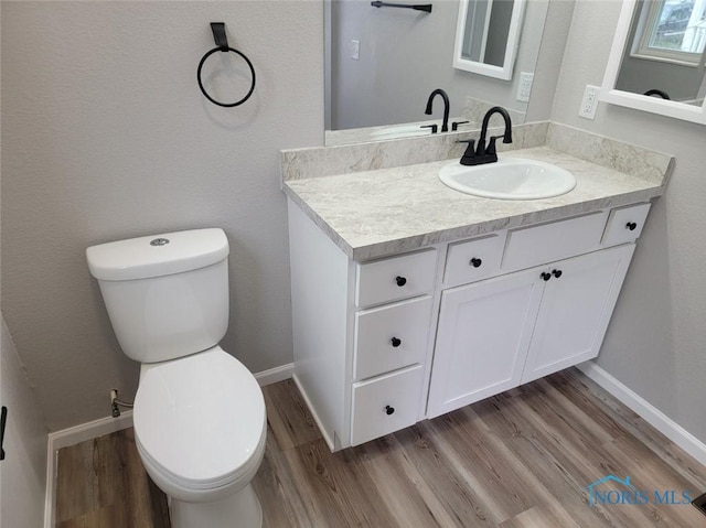 half bathroom with wood finished floors, toilet, and baseboards