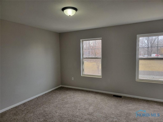 carpeted empty room with visible vents and baseboards