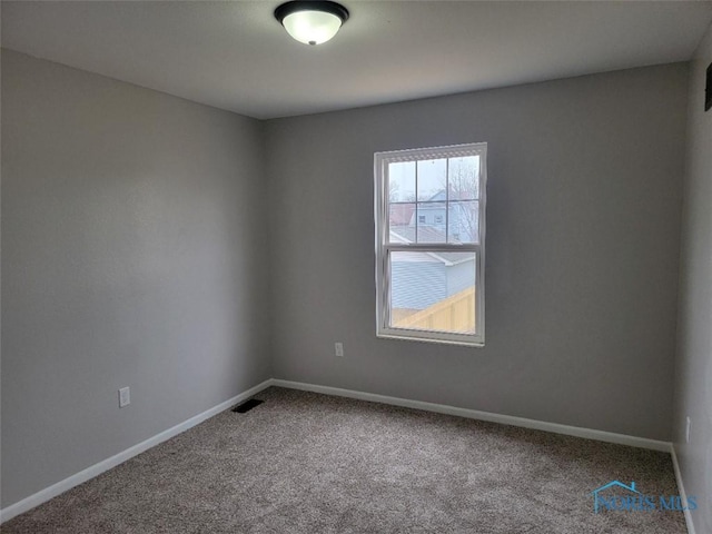 carpeted spare room featuring visible vents and baseboards